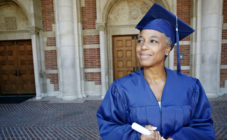 Una donna sorridente in possesso di un diploma in un abito di laurea