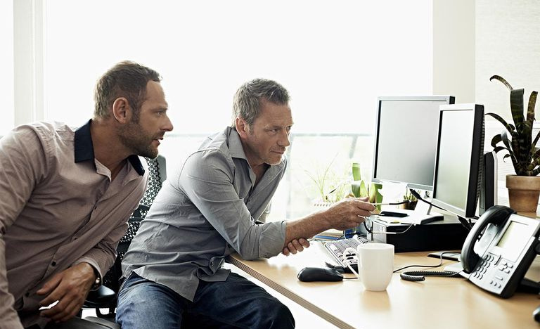Medarbeidere diskuterer data på datamaskinen
