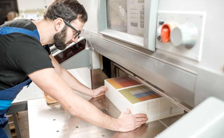 Mężczyzna układa papier w prasie drukarskiej