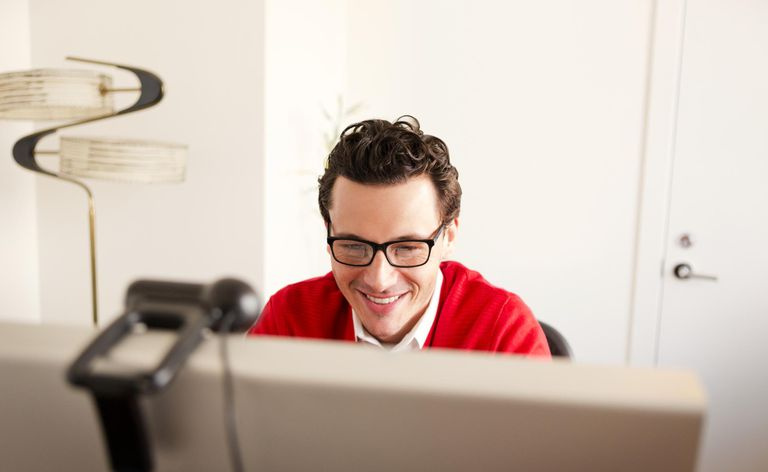 Osoba uśmiechająca się podczas korzystania z komputera i transmisji na żywo za pomocą kamery internetowej