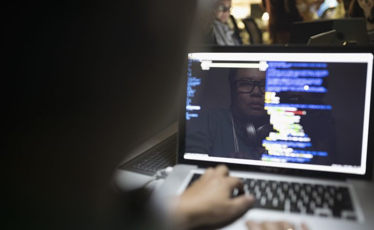 Odbicie kobiecego hakera kodującego hackathon na laptopie