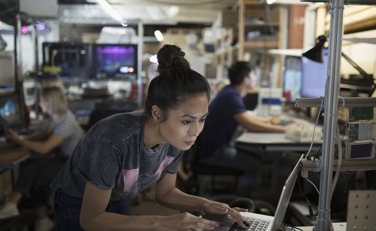 Fokusert kvinnelig ingeniør som jobber på bærbar PC i verkstedet