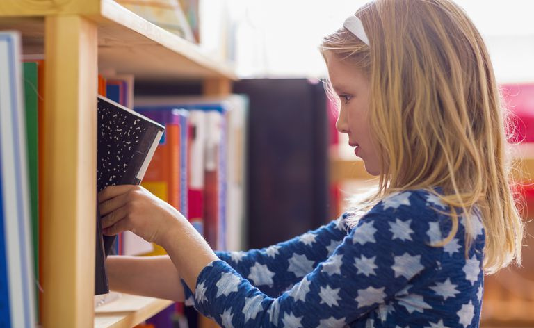 Jauns students ievieto grāmatu klases bibliotēkā.