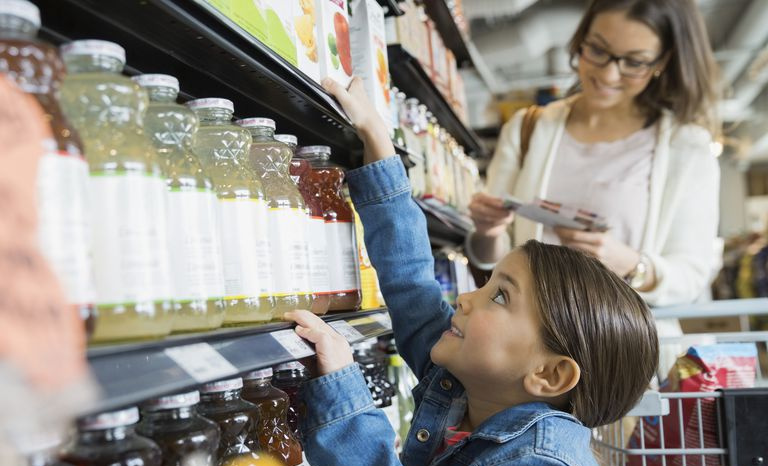 Ragazza che cerca il succo sullo scaffale nel mercato