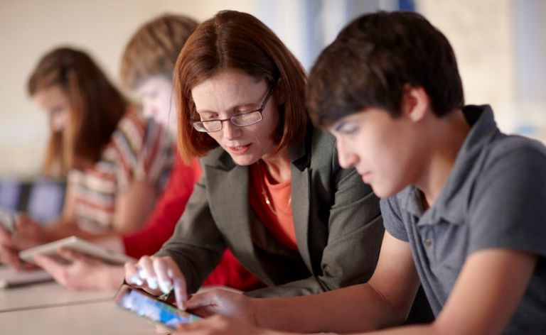Un profesor ayudando a un estudiante en un ipad.