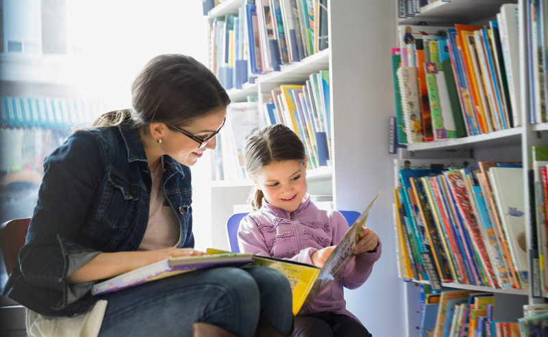Mutter und Tochter lesen Buch im Buchladen