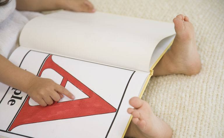 アルファベットの本の文字 A を指している幼い子供
