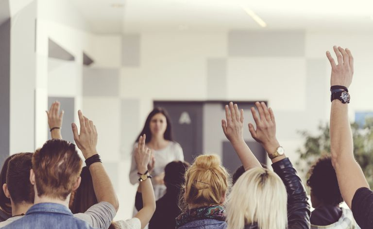 Nauczyciel przed klasą z podniesionymi rękami