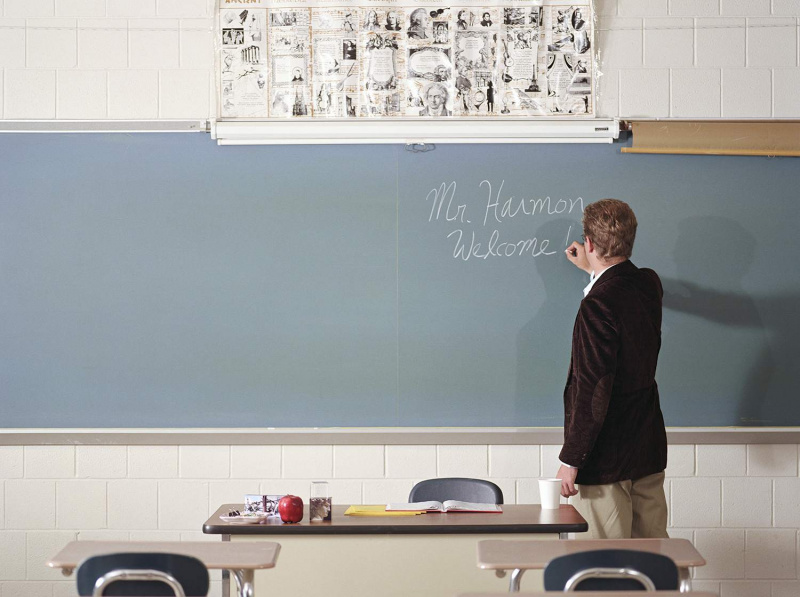 Profesor escribiendo el nombre en la pizarra el primer día de clase, vista trasera