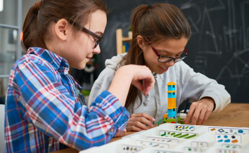 Meninas inteligentes fazendo torre de blocos de construção