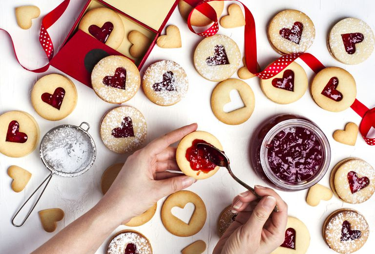 Galleta Linzer tradicional con mermelada de fresa, vista superior. Manos femeninas haciendo galletas.