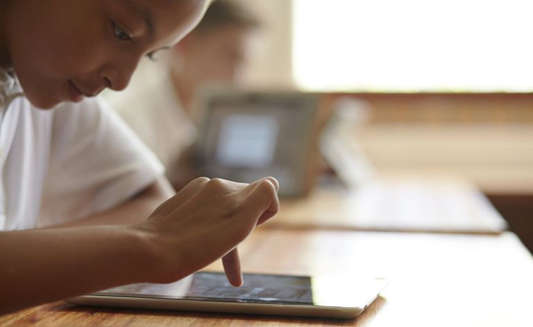 Nahaufnahme eines Schulmädchens, das auf einem Tablet scrollt