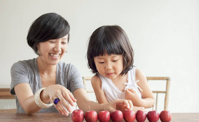 Mãe e filho com um grupo de maçãs seguidas em uma mesa
