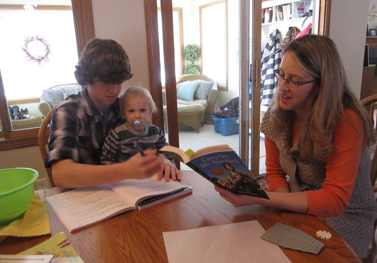Mutter, Sohn und Kleinkind während einer Homeschooling-Stunde.
