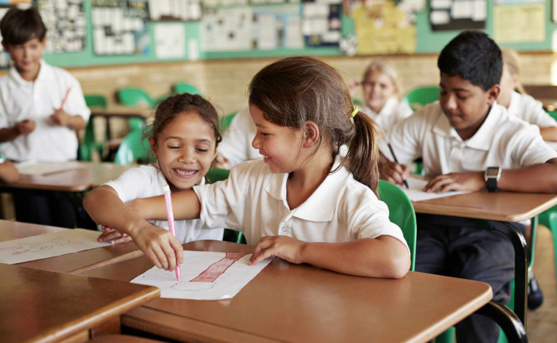 Colegialas dibujando en el papel de los demás