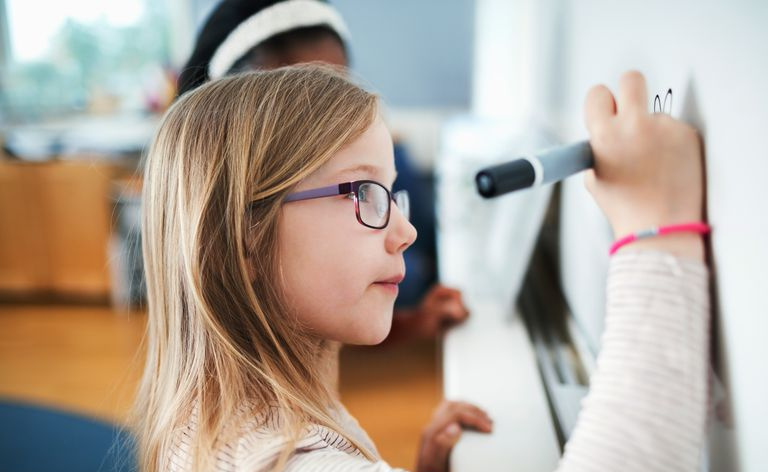 primer plano, de, niña, llevando anteojos, escritura, en, pizarra, en, aula