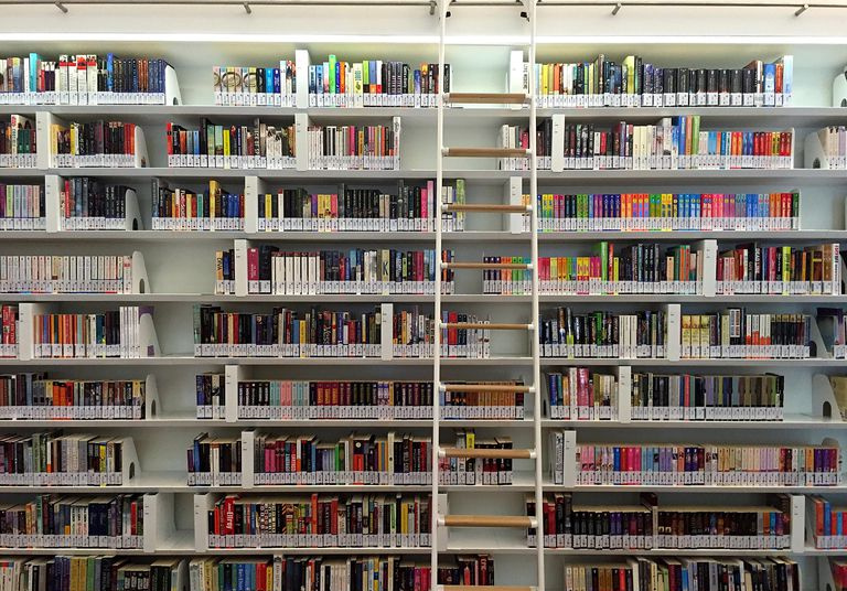 Una escalera contra estantes de biblioteca altos