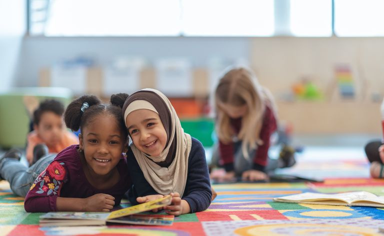 Duas meninas estão deitadas no tapete em sua sala de aula