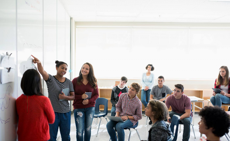 Estudiantes de secundaria dando pizarra de presentación en el aula
