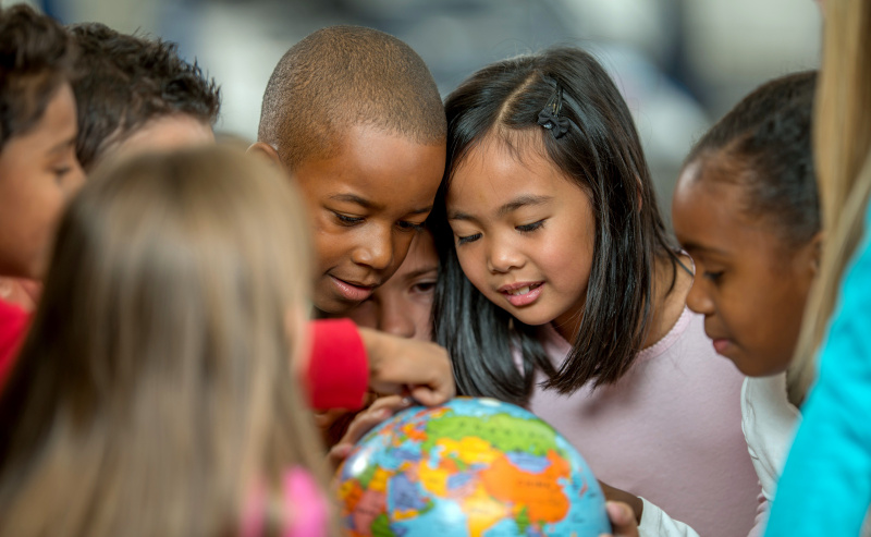 Gli studenti della scuola primaria imparano a conoscere i paesi e la geografia esaminando un globo