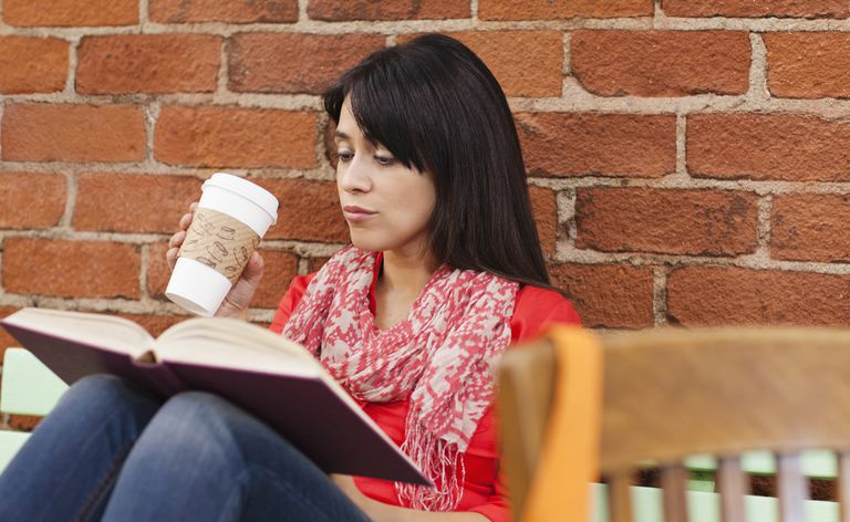 Frau liest Buch und trinkt Kaffee