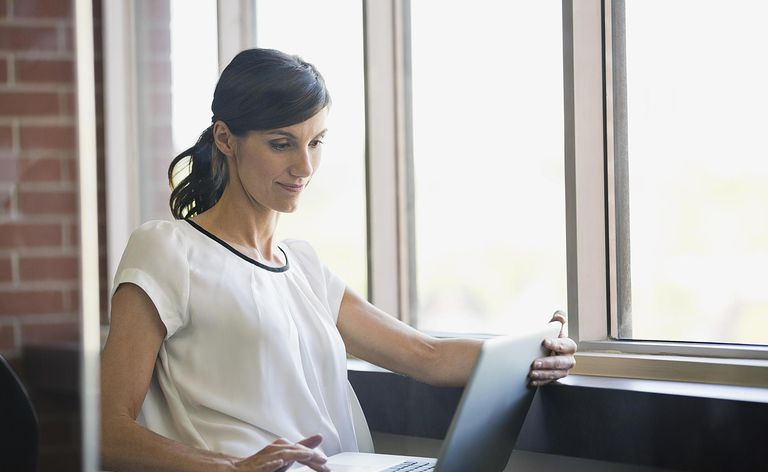 Mulher de negócios usando laptop pela janela no escritório