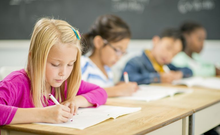 Uczniowie szkół podstawowych pracujący przy biurkach