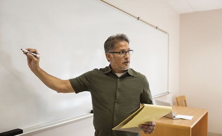 Profesor pisze na tablicy w klasie