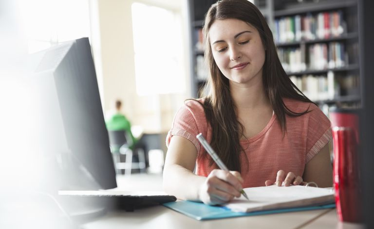 Studentka pisząca notatki w segregatorze w bibliotece uniwersyteckiej