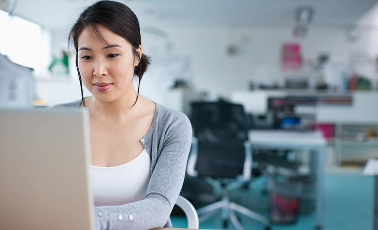 Donna di affari sorridente che lavora al computer portatile in ufficio