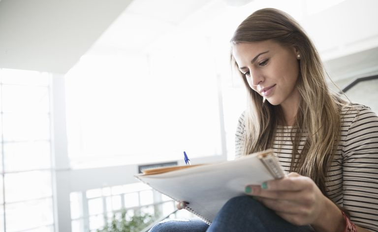 Studentin schreiben Notizen in Notizbuch auf dem College-Campus