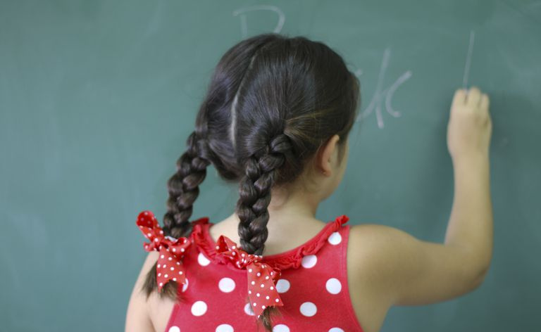 Fille écrivant sur le tableau noir à la salle de classe