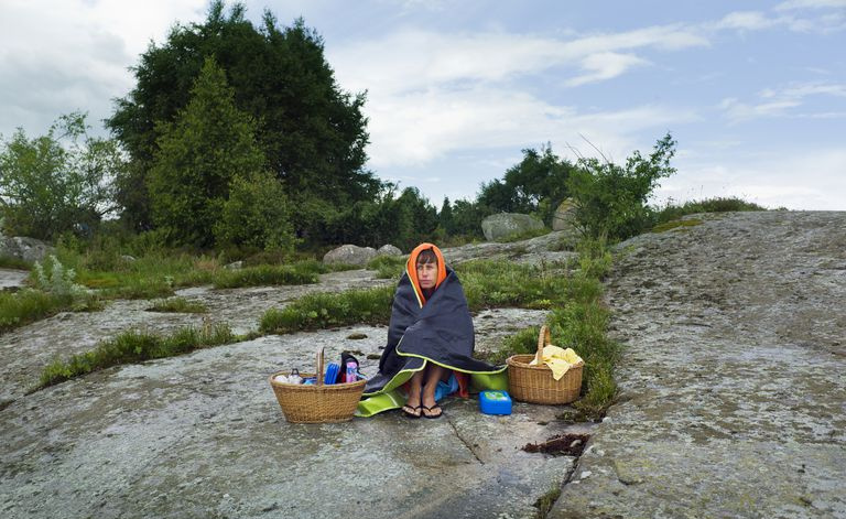 hombre que sienta, en, roca, con, cestas de picnic