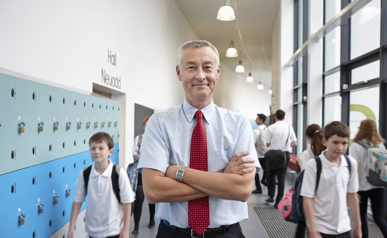 Portrett av mannlig lærer med armene foldet i skolekorridoren