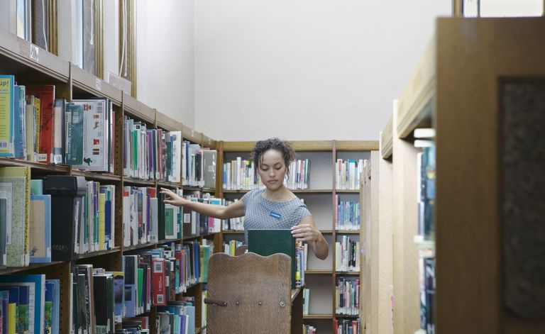 Hembra joven liberiana arreglando libros en una biblioteca