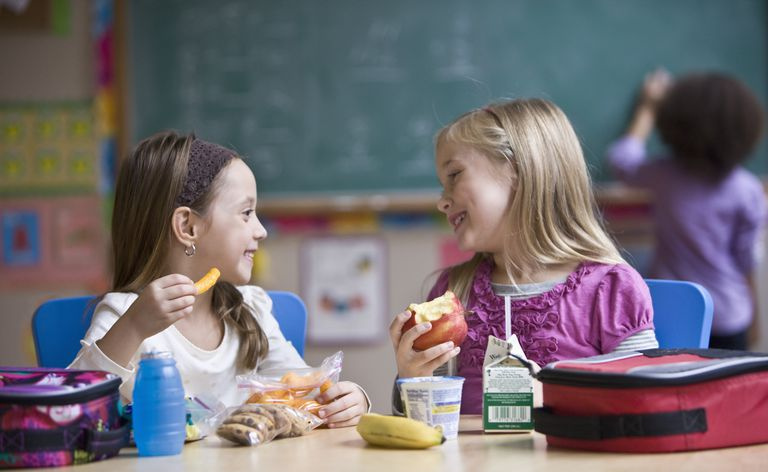 Meitenes ēd skolā pusdienu līdzņemšanu