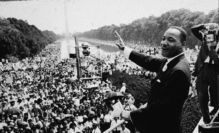 Martin Luther King, Jr. na marszu nad Waszyngtonem macha do tłumu, czarno-biała fotografia.
