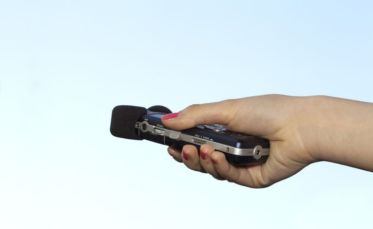 Roku turot digitālo balss ierakstītāju uz gaiši zila fona