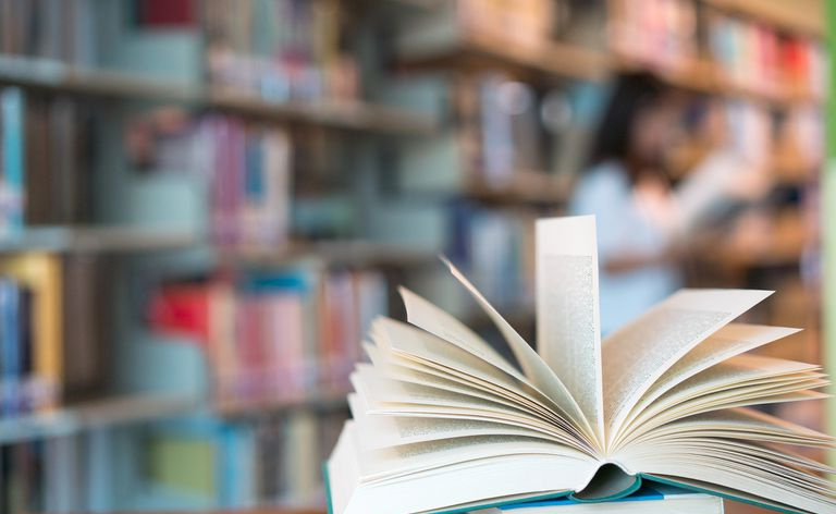 Buchen Sie in der Bibliothek mit altem offenem Lehrbuch