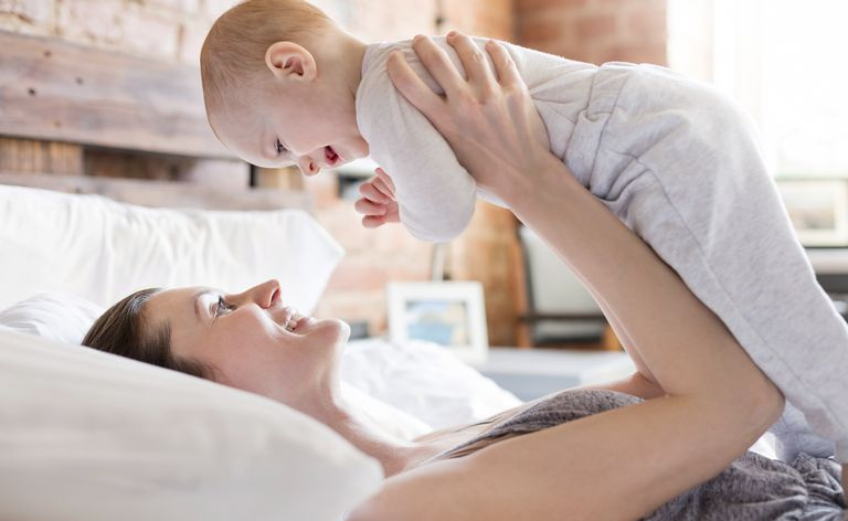 Mère souriante tenant sa petite fille au-dessus du lit