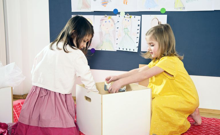 Kinder räumen Spielzeug weg