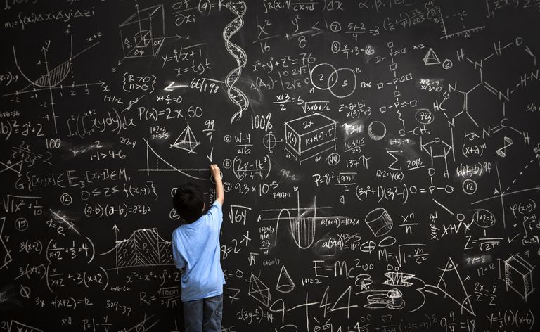 Ung gutt skriver matematiske ligninger på tavlen