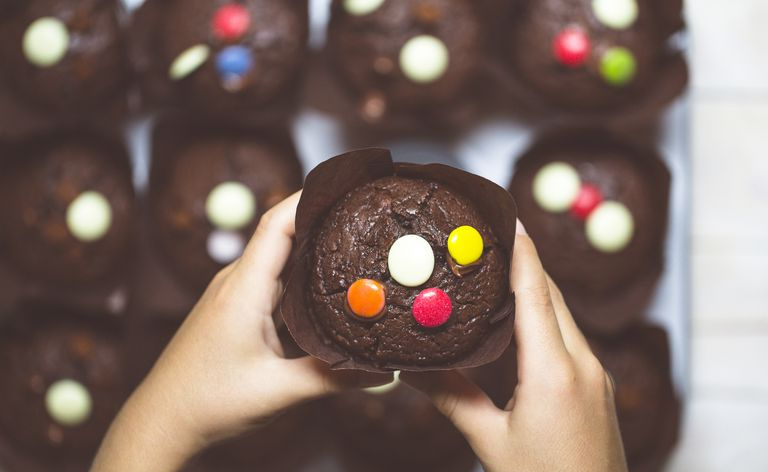 Mains de garçons prenant un muffin aux pépites de chocolat dans un plateau à muffins