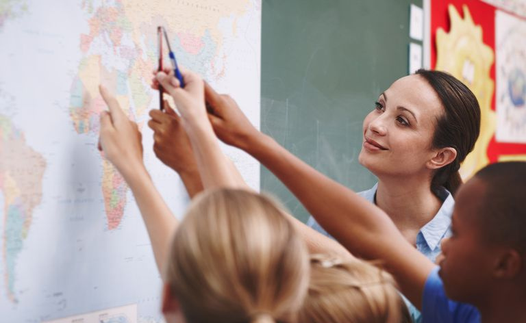 Un insegnante supervisiona gli studenti indicando i paesi su una mappa del mondo