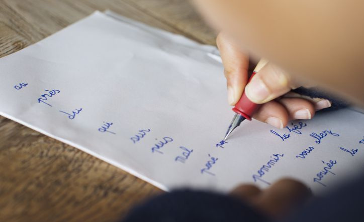 Kind schreibt in Schreibschrift auf Papier, beschnitten