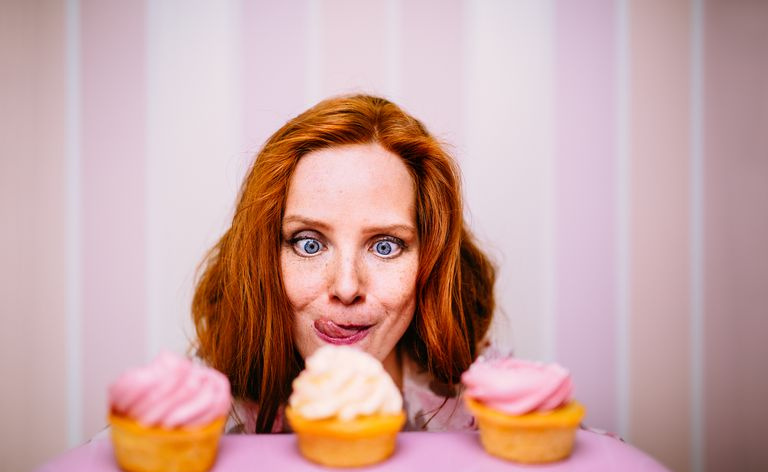 Junge rothaarige Frau möchte wirklich rosa Cupcakes essen