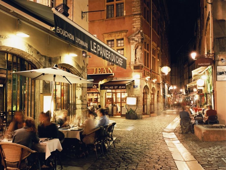 Lyon, les gens dînant le long de la rue pavée la nuit