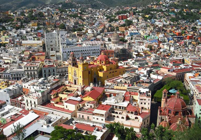 Veduta aerea di una trafficata cittadina del Messico circondata da montagne e alberi.