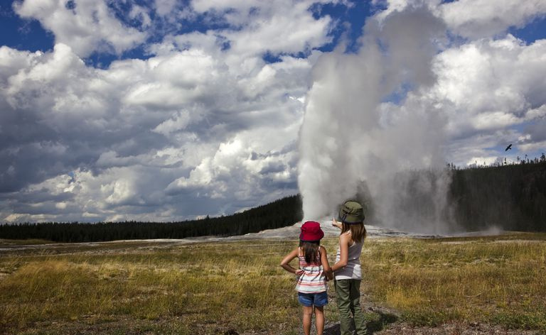 Divas jaunas meitenes skatās, kā Old Faithful izvirst