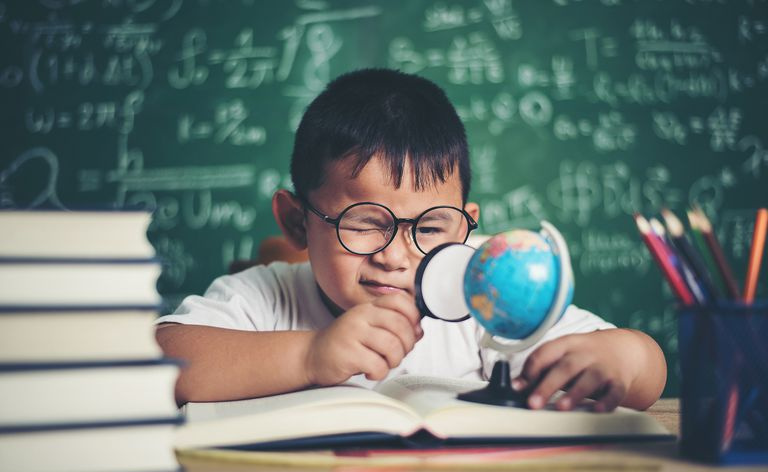 黒板に対してテーブルで勉強している少年